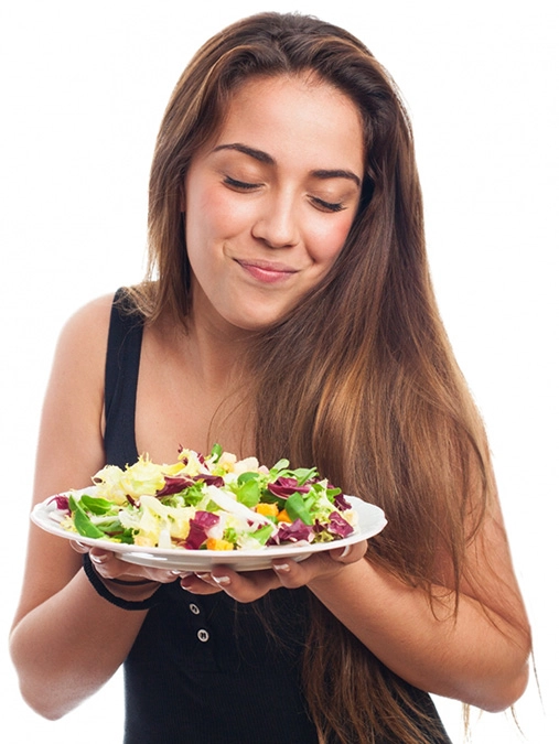 Moa jovem com prato de comida nas mos e uma expresso de satisfao ao sentir o aroma do alimento.